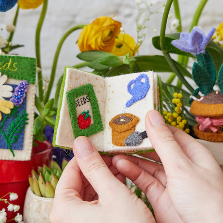 Handmade felt gardening book ornament with embroidered seed planting and watering illustrations