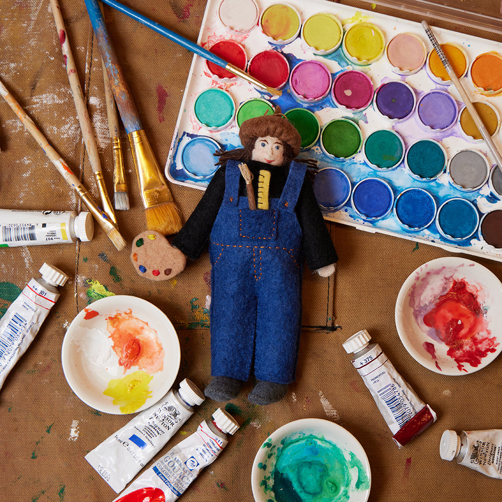 Hand-felted artist ornament holding a paintbrush and palette, celebrating creativity and handmade craftsmanship. Made from sustainable wool felt.