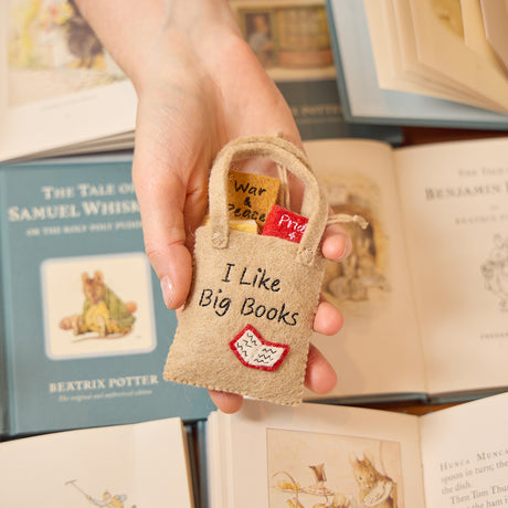 Handmade felt ornament shaped like a tote bag filled with miniature felt books, including titles like Pride & Prejudice and War & Peace. Crafted from soft merino-blended wool, this quirky ornament is a playful nod to literary humor. Perfect for bookworms, teachers, librarians, and pun enthusiasts, it adds a clever touch to holiday trees, bookshelves, or classrooms. Ready to hang with a string attached.