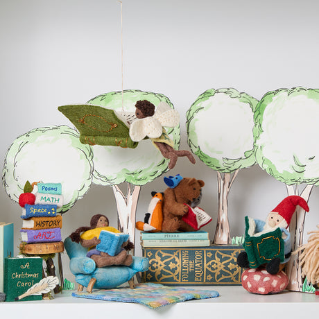 Handmade felt ornament of a fairy with delicate wings and a leafy green tunic, reading an oversized open book embroidered with whimsical details. Featured with  other adorable readers and a stack of books. Perfect for fairy collectors, book lovers, and dreamers, it brings a magical, literary touch to bookshelves, holiday trees, or cozy reading spaces. Ready to hang with a string attached.