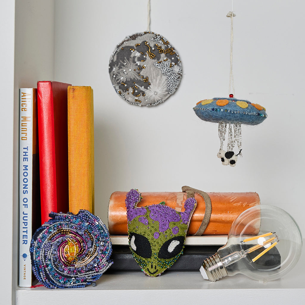 Felted wool UFO ornament with vibrant stitching and playful beading, perfect for sci-fi lovers and quirky decor.