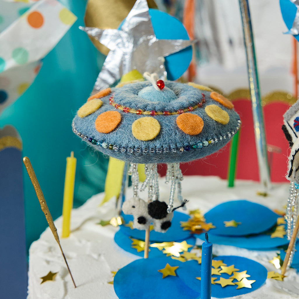 Cosmic wool UFO ornament with abduction motif, colorful details, and hanging string, made by Kyrgyz artisans.