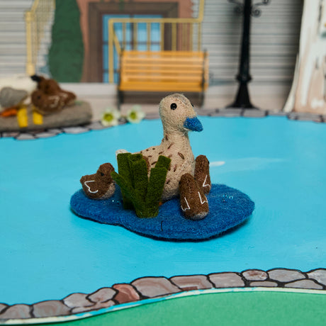Storybook-inspired duck ornament featuring a mother duck and ducklings in a felted wool pond setting.