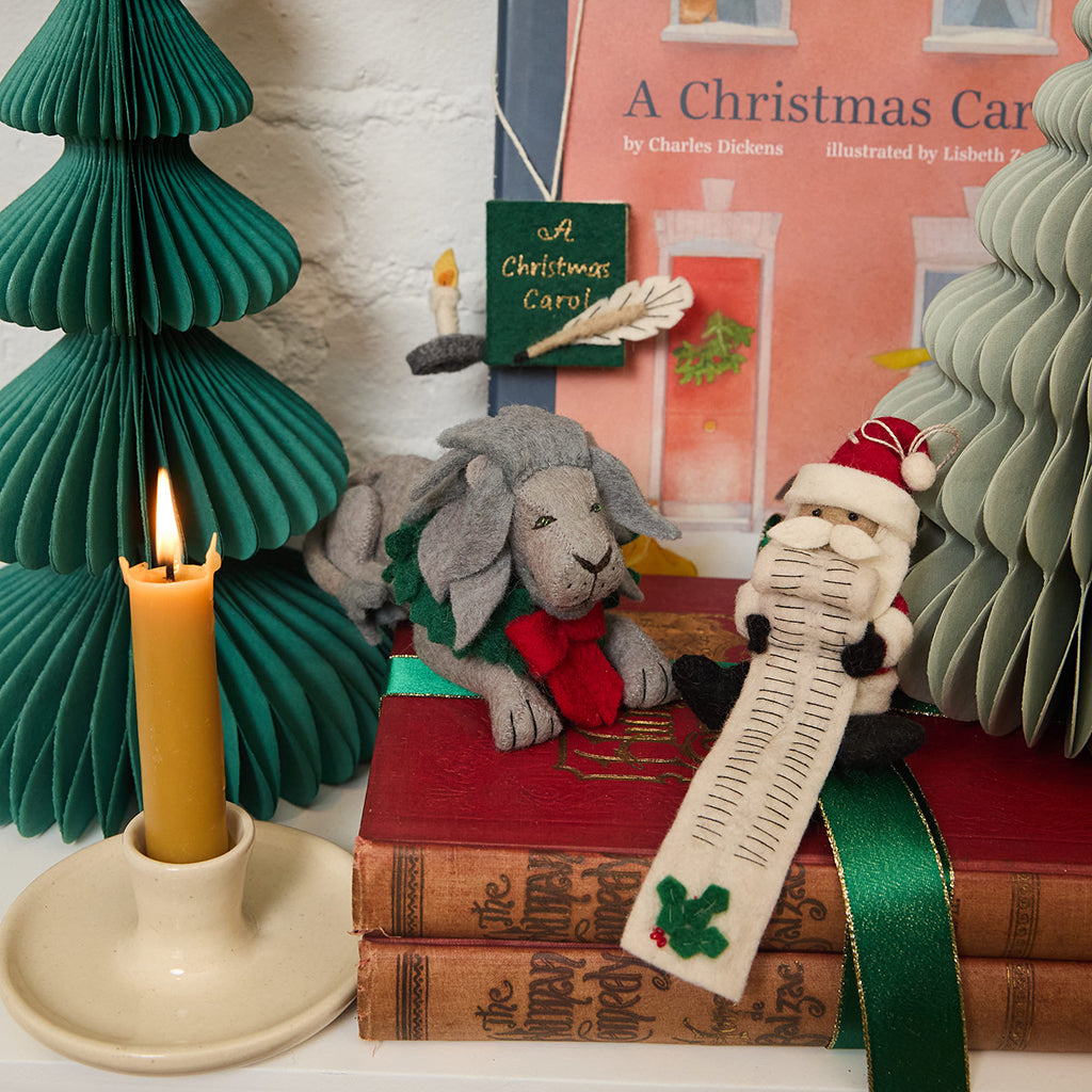 Handmade felt ornament of a regal lion statue adorned with a festive holiday wreath, inspired by the iconic lions outside the New York Public Library. Crafted from merino-blended wool, this ornament captures the spirit of NYC, literary tradition, and holiday cheer. A thoughtful gift for book lovers, librarians, and New York enthusiasts, perfect for trees, bookshelves, or desks. Ready to hang with a string attached. featured with Santaand his long list of children