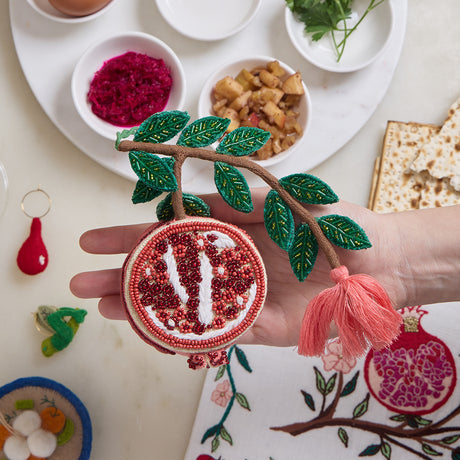 Beaded pomegranate decoration with leaf accents and linen texture, ethically made for celebrating tradition and prosperity.