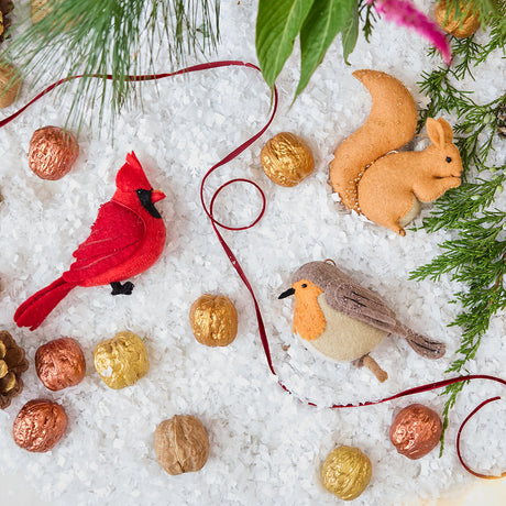 Craftspring’s handmade felt Red Squirrel, Cardinal, and Robin ornaments — featuring delicate beaded and embroidered details, displayed with evergreens and golden walnuts for a festive woodland holiday scene, perfect for Christmas decorating or gifting, ethically crafted by artisans using sustainable wool.