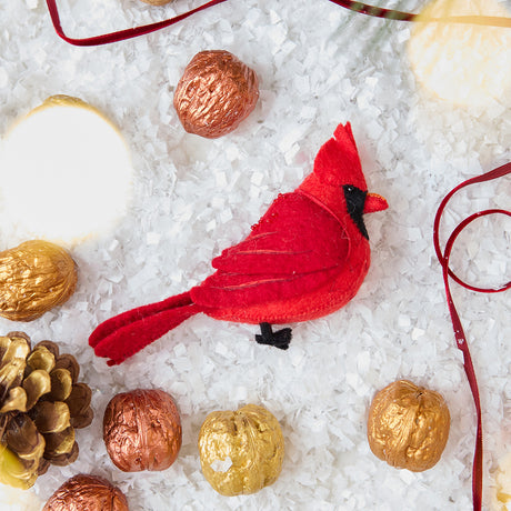 Craftspring’s handmade felt Cardinal ornament — featuring delicate beaded and embroidered details, displayed with a red ribbon and golden walnuts for a festive holiday scene, perfect for Christmas decorating or gifting, ethically crafted by artisans using sustainable wool.