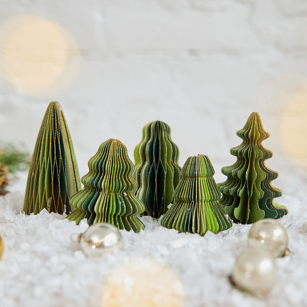Craftspring’s Green Honeycomb Paper Mini Trees — Set of 5, displayed on snow with Christmas bobbles, showcasing their shades of green, gold edges, and unique shapes — handmade by artisans from recycled cotton waste for a festive holiday scene, perfect for gifting.
