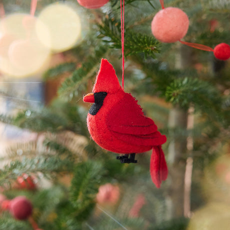 Craftspring’s Cardinal ornament — featuring delicate beaded and embroidered details, displayed on a Christmas tree for a festive woodland holiday scene, ethically crafted by artisans using sustainable wool.