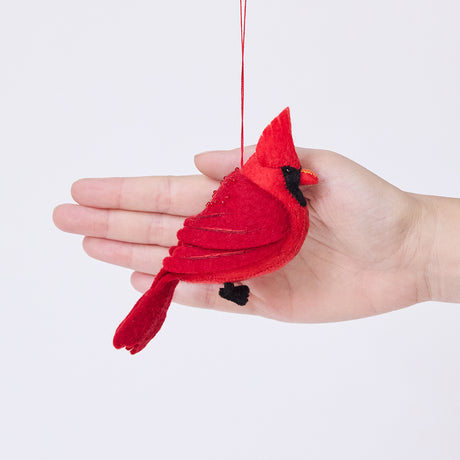 Craftspring’s Cardinal ornament held in front of a hand to show its size—handmade from sustainable wool with delicate beaded and embroidered details, ethically crafted by artisans using sustainable wool.