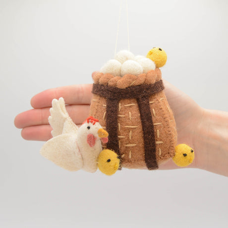 Wool ornament of mother hen carrying eggs and chicks, inspired by traditional Adirondack pack baskets.