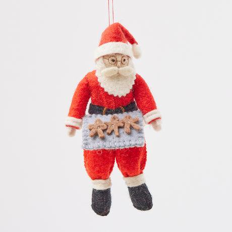 A hand-embroidered Santa Claus Christmas ornament with a red suit, white beard and hat, holding a baking tray with cookies, made from merino-wool.