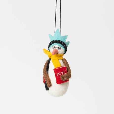 Handmade felt ornament of a snowman with round black glasses, a Statue of Liberty crown, and holding a tiny red book and a black Strand tote bag. Crafted from 100% wool, this whimsical snowman captures the spirit of a New York reader braving the winter with book and tote in hand. Perfect for book lovers, NYC fans, and anyone who cherishes The Strand bookstore, this ornament adds a literary twist to holiday decor. Ready to hang with a string attached.