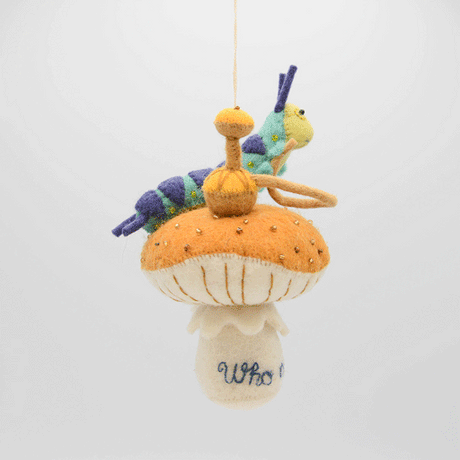 Hand-felted wool ornament of the Caterpillar from Alice in Wonderland, perched on a red-and-white mushroom with a hookah beside him. Features detailed embroidery and the phrase 'Who are you?' stitched at the base. Made from natural merino-blend wool, this whimsical ornament includes a hanging string and measures approximately 5.5 inches tall. GIF 360 degree view