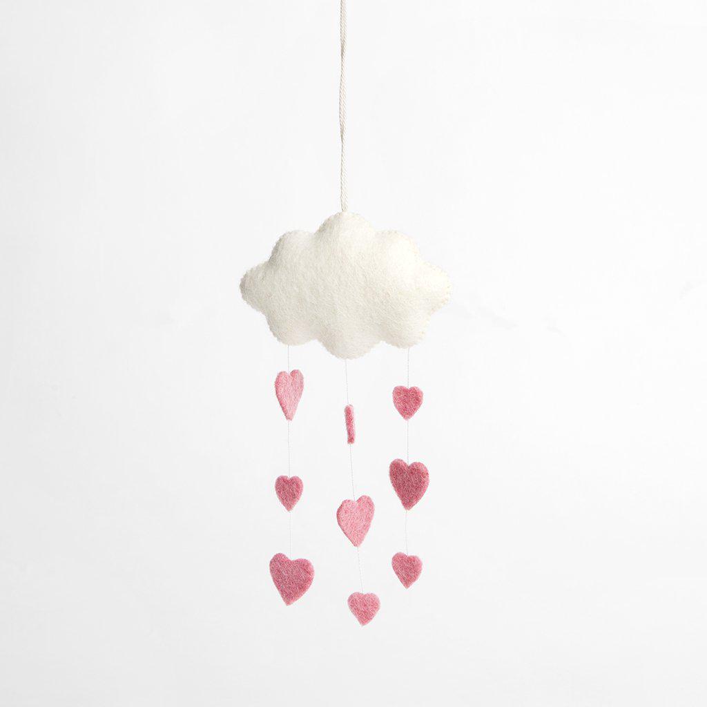 A handmade felt white cloud ornament snowing down three strings of pink hearts
