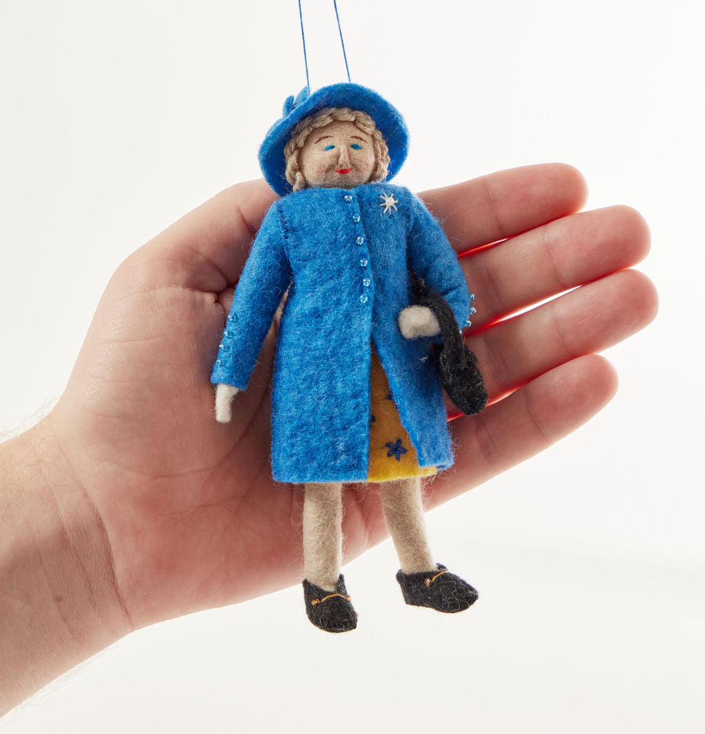 Queen Elizabeth II felt ornament wearing royal blue coat and hat, with black handbag and detailed embroidery. Handmade wool Christmas ornament honoring British royalty. Fair trade and ready to hang. Held in a hand for scale and size reference.