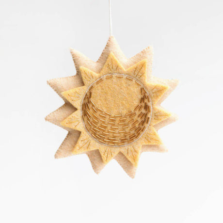 Handmade felt sun ornament with golden embroidery, symbolizing renewal and vitality, crafted from natural wool.