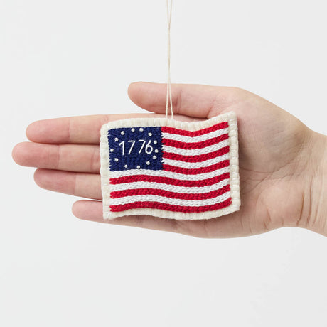Honor the spirit of 1776 with our handcrafted 1776 American Flag Ornament from the Craftspring Semiquincentennial Collection. Inspired by the early American flag associated with the Revolutionary era, this felt ornament features embroidered red and white stripes, a blue canton with stars, and the year “1776” stitched proudly across the center—commemorating the birth of the United States. 