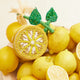 Bright citrus ornament featuring intricate beadwork, green leaves, and a lemon blossom tassel, handcrafted in India.