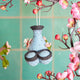Felt sake pitcher and cup ornament with sakura blossom accents, handmade from wool and inspired by Japanese sake traditions.

