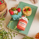 Strawberry-themed felt ornament gift set in a kraft box with crinkle paper. Includes a felt strawberry pint, strawberry jam jar, and strawberry pancake stack. Handmade from natural wool felt using traditional needle-felting. Fair trade and ready to hang.