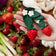 Pair of hand-felted wool strawberries, each detailed with embroidered seeds, stitched stems, and leafy green tops. These vibrant red berries, measuring 4.5 inches tall, evoke summertime berry picking and garden freshness. A sweet gift for foodies, kids, or lovers of handmade seasonal décor.