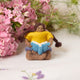 Handmade felt ornament of a young girl sitting cross-legged, absorbed in a book. Crafted from natural merino-blended wool, her focused gaze and relaxed posture capture the magic of reading. With braided brown hair and a warm-toned complexion, this ornament adds a cozy, literary touch to reading nooks, desks, or shelves. A perfect gift for bookworms, young readers, or anyone who treasures the quiet joy of a good story. Ready to hang with a string attached.