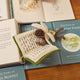 Handmade felt ornament of a fairy with delicate wings and a leafy green tunic, reading an oversized open book embroidered with whimsical details. Crafted from merino-blended wool, this limited-edition ornament is full of storybook charm. Perfect for fairy collectors, book lovers, and dreamers, it brings a magical, literary touch to bookshelves, holiday trees, or cozy reading spaces. Ready to hang with a string attached.