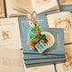 Handmade wool ornament of Peter Rabbit, featuring the beloved children's book character sitting with a carrot in one paw and an embroidered book on his lap. He wears his signature blue jacket, crafted with detailed stitching. Made from natural felted merino-blend wool, the ornament is ready to hang and sized approximately 4.5 inches tall.