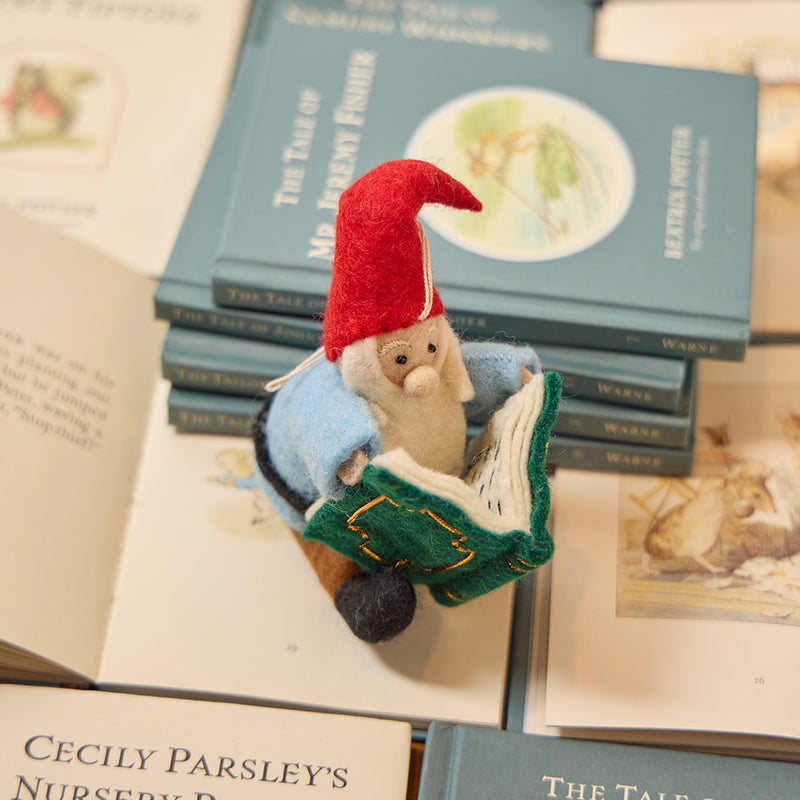 Handmade felt ornament of a gnome with a tall pointy hat, peacefully reading a large green book. Crafted from soft merino-blended wool, this whimsical figure captures the quiet magic of storytelling. A cozy gift for book lovers, librarians, and educators, perfect for hanging on holiday trees or displaying in reading nooks and bookshelves. Ready to hang with a string attached.

