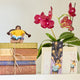 Girl reading in sitting position, part of the Reading-themed gift bundle featuring four handmade wool felt ornaments—a gnome reading a book, a lion with glasses holding a book, a young girl reading, and a fairy with wings reading—alongside a coordinating stationery set. Stationery includes a notepad, four illustrated notecards with envelopes, and four colorful bookmarks, all featuring characters from the Reading Collection. Ornaments are made from natural merino-blend wool and come ready to hang.