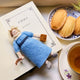 Handcrafted felt ornament of Jane Austen, featuring the beloved author standing with a feather quill in one hand and a felt copy of Pride and Prejudice in the other. She wears a period-style dress and bonnet, all made from natural merino-blend wool with fine stitched details. Includes a string for hanging and measures approximately 6 inches tall.