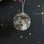 Hand-beaded moon ornament featuring embroidered craters and lunar phases. Handmade astronomy-themed décor crafted from linen and beads.

