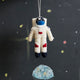 Space-themed astronaut ornament made from wool felt, featuring stitched stars and helmet. Ideal for STEM gifts, holiday décor, and science classrooms.

