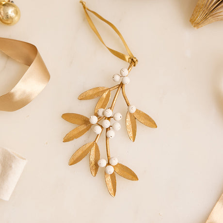 Add a little holiday romance to the tree with our Mistletoe Metal Ornament. Inspired by vintage botanical decorations, this delicate golden mistletoe is beautifully handcrafted with embossed iron leaves, hand-cast resin details, and a softly aged gilt finish.