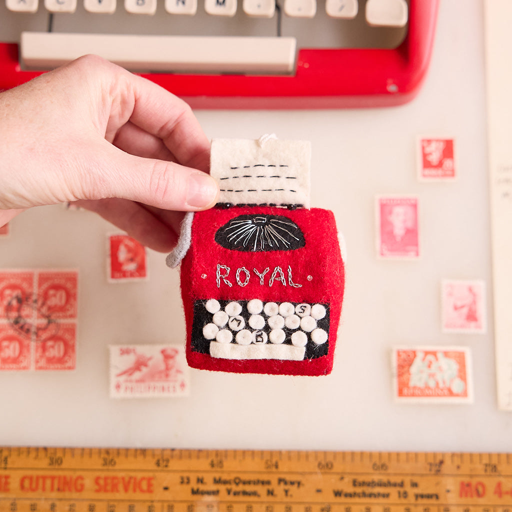 Felt red typewriter ornament with embroidered keys and retro design, handmade wool décor perfect for writers, book lovers, and holiday gifts.

