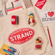 Handmade felt ornament shaped like The Strand Bookstore tote bag, a Strand NYC guide book and  NYC snowman tourist with its own Strand tote bag.  Crafted from soft tan wool felt, this miniature tote is filled with colorful hand-felted books, paying tribute to the legendary NYC bookstore. A perfect gift for Strand fans, NYC lovers, and book enthusiasts, adding a literary touch to holiday trees or bookshelves.

