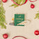 Miniature hand-felted wool ornament shaped like an open book titled A Christmas Carol, featuring embroidered details including a writing plume and a golden chamberstick. Crafted from merino-blend wool with a hanging string, the ornament evokes Victorian charm and the classic story of Ebenezer Scrooge. Measures approximately 2.25 inches high and 3.75 inches wide.
