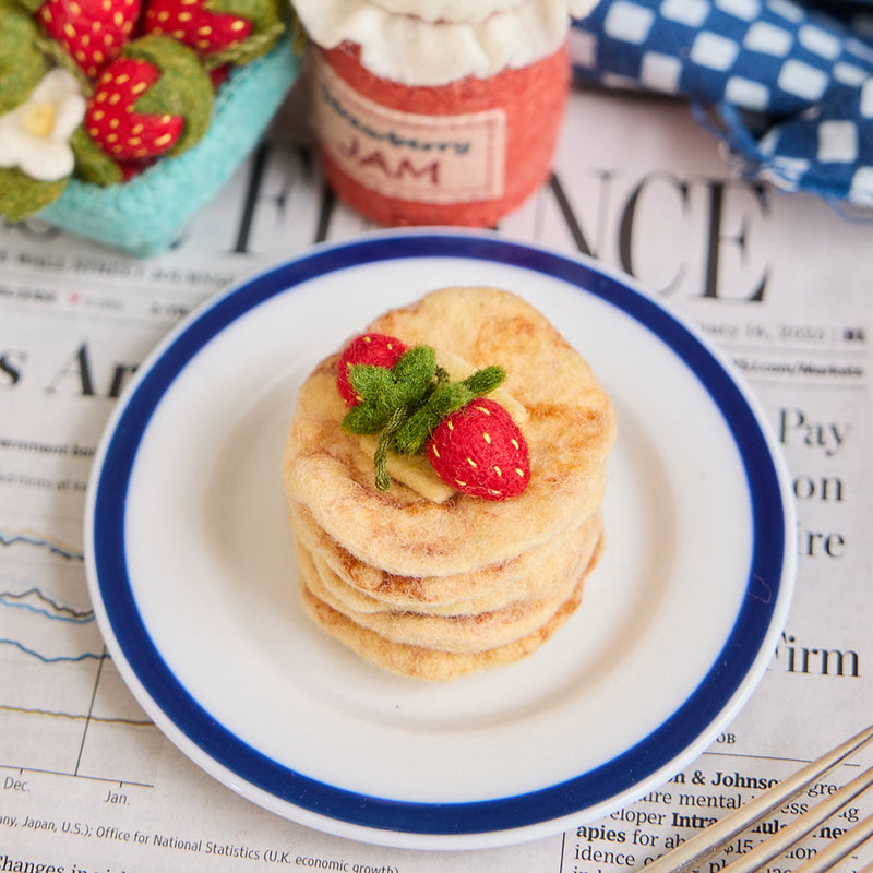 Hand-felted ornament featuring a stack of golden-brown pancakes topped with red strawberries and a square of butter. Made from natural merino-blend wool, this 1.75-inch tall breakfast-themed decoration is perfect for foodies, brunch lovers, and cozy summer gifting.