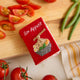 Miniature felt ornament shaped like a cookbook, hand-felted and embroidered with cooking-themed details including salt, pepper, vegetables, and a stovetop. Crafted from merino-blend wool with soft pages and a hanging string, this ornament measures approximately 2.5 inches tall. A cozy tribute to home cooking and culinary tradition.