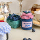Felt blueberry pint ornament with hand-felted blue berries in a soft green wool basket alongside a felt blueberry jam ornament. Handmade from natural wool felt using traditional needle-felting. Fair trade and ready to hang.