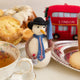 London snowman felt ornament wearing a black top hat and Union Jack tie, holding a teacup and umbrella. Handmade wool Christmas ornament with British charm. Fair trade and ready to hang.