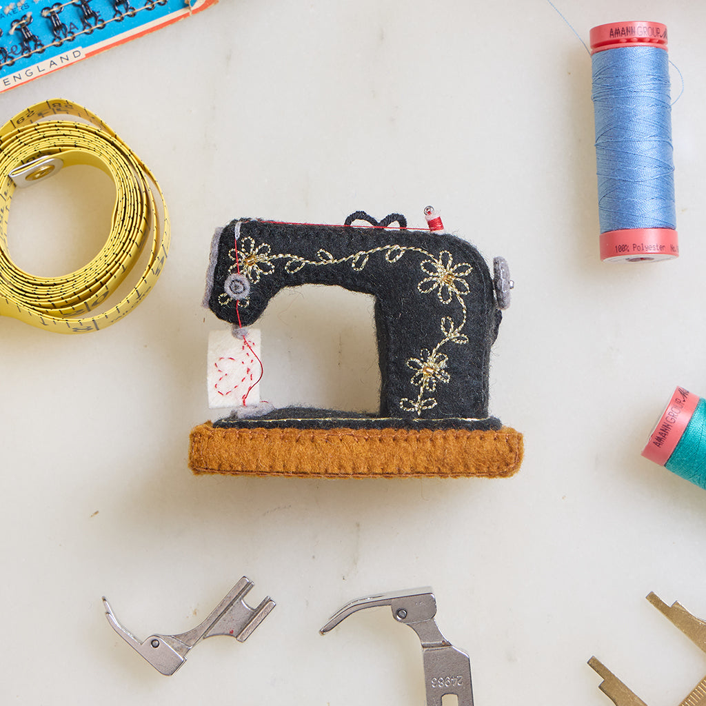 Hand-felted antique sewing machine Christmas ornament with gold embroidery and tiny thread spool, handmade by women artisans