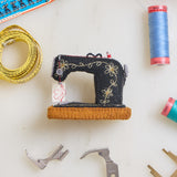 Hand-felted antique sewing machine Christmas ornament with gold embroidery and tiny thread spool, handmade by women artisans