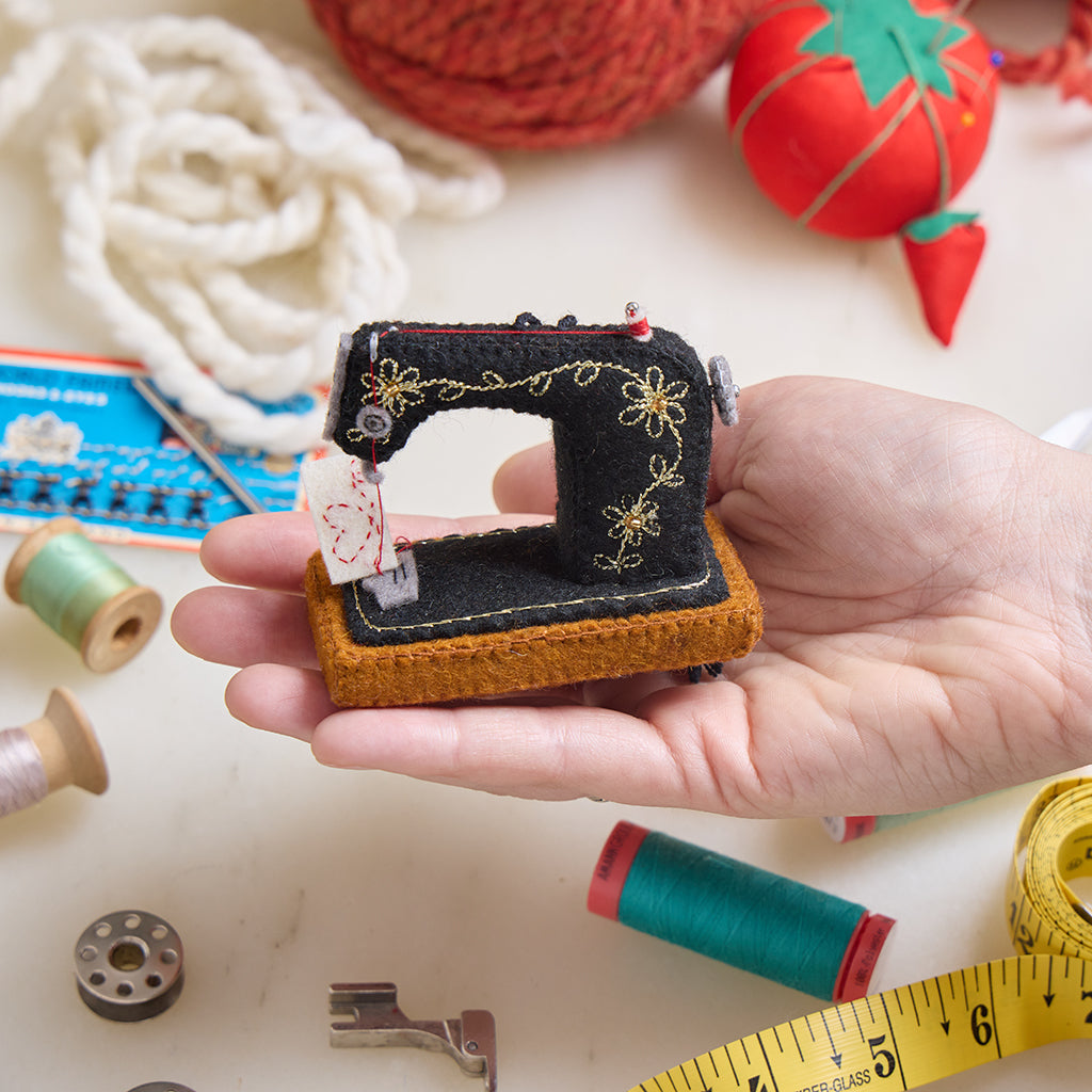 Cute as can be handmade antique sewing machine ornament with gold embroidery and tiny thread spool, handmade by women artisans, sewing a heart