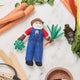 Felt Santa ornament in garden overalls holding a carrot—handcrafted for nature-themed Christmas trees