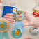 Handmade felt reading badge shaped like a ribbon with shimmering star details, designed to celebrate young readers' achievements. Crafted from merino-blended wool, the badge comes pinned to an illustrated postcard with space for a personal message, and includes an envelope for gifting. Features both a safety pin and a hanging loop. A fun, motivational keepsake for children, perfect for classrooms, libraries, or reading milestones.
