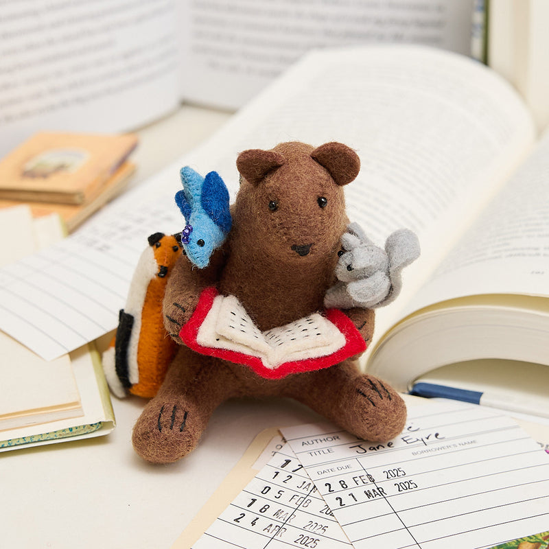Handmade felt ornament featuring a cozy scene with a bear reading a book, surrounded by woodland friends. Crafted from eco-friendly wool, this ornament captures the magic of shared reading and childhood adventures. A heartwarming gift for book-loving families, young readers, and those who cherish the joy of storytelling. Ready to hang with a string attached, it adds a whimsical touch to holiday trees and reading spaces.