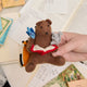 Handmade felt ornament featuring a cozy scene with a bear reading a book, surrounded by woodland friends. Crafted from eco-friendly wool, this ornament captures the magic of shared reading and childhood adventures. A heartwarming gift for book-loving families, young readers, and those who cherish the joy of storytelling. Ready to hang with a string attached, it adds a whimsical touch to holiday trees and reading spaces.