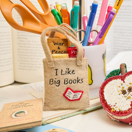 Handmade felt ornament shaped like a tote bag filled with miniature felt books, including titles like Pride & Prejudice and War & Peace. Crafted from soft merino-blended wool, this quirky ornament is a playful nod to literary humor. Perfect for bookworms, teachers, librarians, and pun enthusiasts, it adds a clever touch to holiday trees, bookshelves, or classrooms. Ready to hang with a string attached.